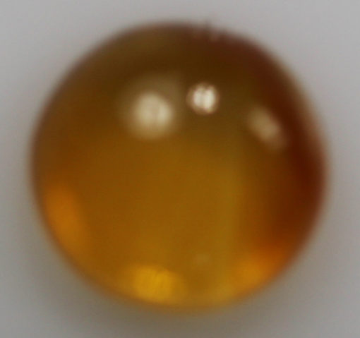 A round yellow stone on a white surface.