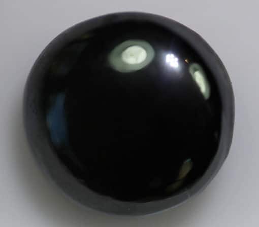 A black gemstone on a white surface.