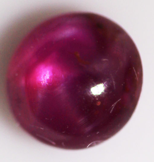 A purple gemstone on a white surface.