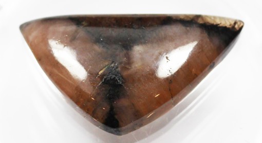 A brown triangular shaped stone on a white surface.