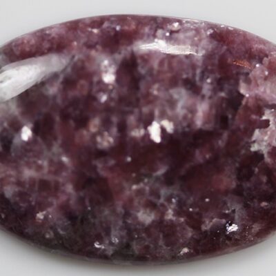 An oval shaped purple stone with a speckled surface.