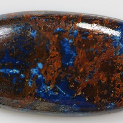 A blue and brown lapis stone on a white surface.