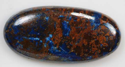 A blue and brown lapis stone on a white surface.