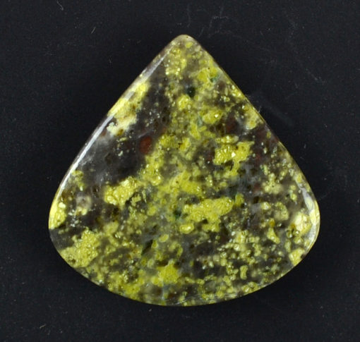 A piece of yellow jasper on a black surface.