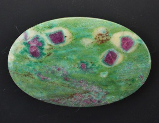A green and pink stone pendant on a black background.