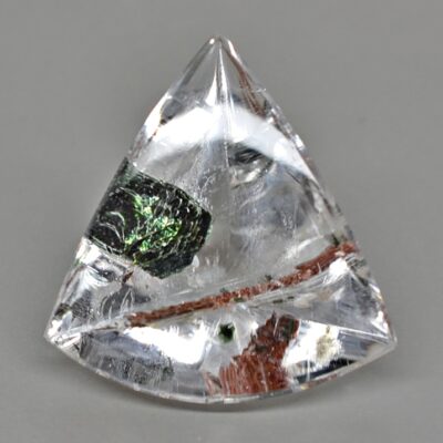 A triangular shaped crystal with green and black streaks.