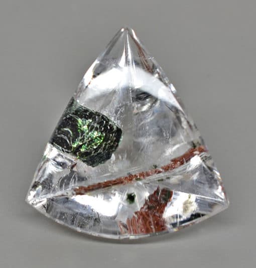 A triangular shaped crystal with green and black streaks.
