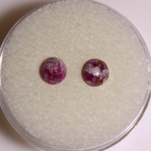 A pair of ruby studs sitting on top of a white surface.