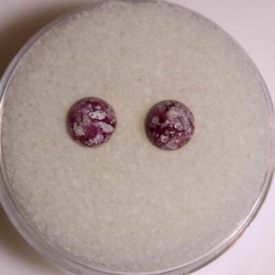 A pair of ruby stud earrings sitting on top of a white surface.
