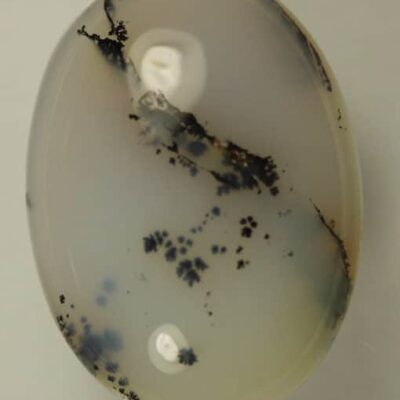 A close-up of a Black Moss Agate 8.10cts Oval Cabochon stone.