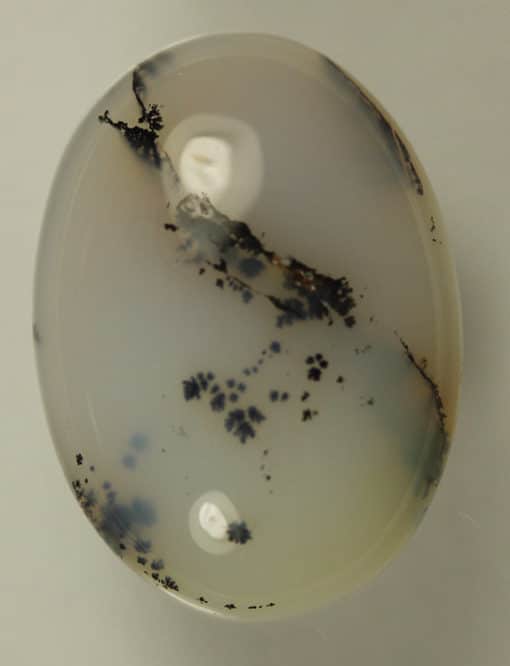 A close-up of a Black Moss Agate 8.10cts Oval Cabochon stone.