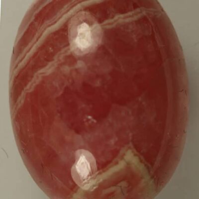 A Rhodocrosite 12.95cts Oval cabochon ball on a white surface.