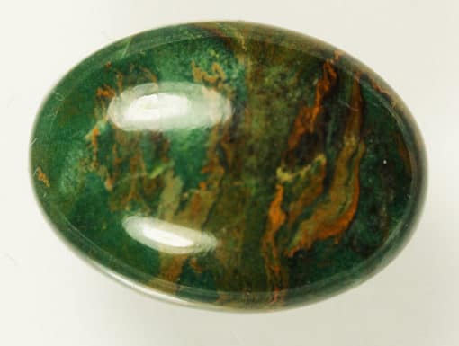 A green and brown jade 9.45cts Oval cabochon ball on a white surface.