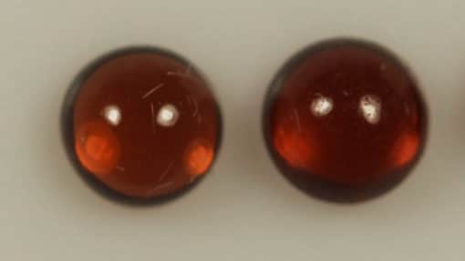 A set of three Almandine Garnets 0.75cts Pair of Round Cabochon 4.00mm Q0344 on a white surface.