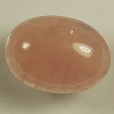 A piece of Rose Quartz 8.90cts Oval Cabochon 18.00 x 13.00mm Q0349 on a table.
