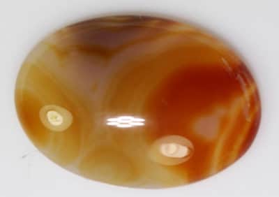 A brown and orange Carnellian 14.91cts Oval Cabochon 25.00 x 18.00 Q0224 on a white surface.