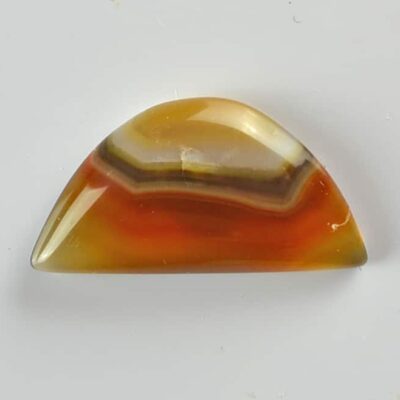 An orange and yellow agate cabochon on a white surface.