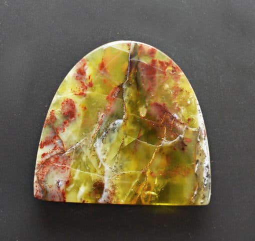A piece of yellow and red agate on a black surface.