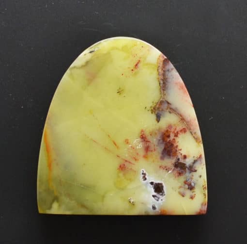 A yellow and red agate piece on a black surface.