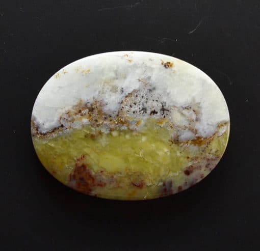 A yellow and white agate oval on a black surface.