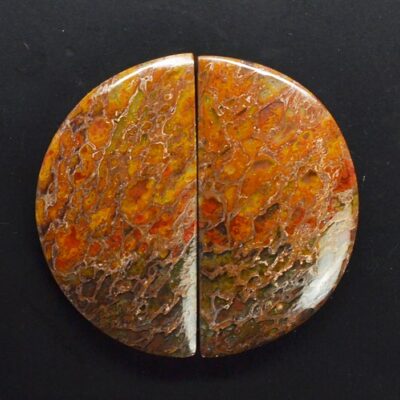 A piece of red and orange jasper on a black surface.