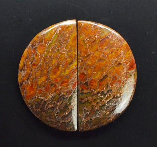 A piece of red and orange jasper on a black surface.