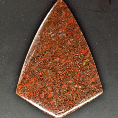 A triangular shaped piece of red and brown stone.