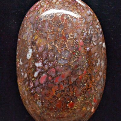 A red and brown stone cabochon on a black background.