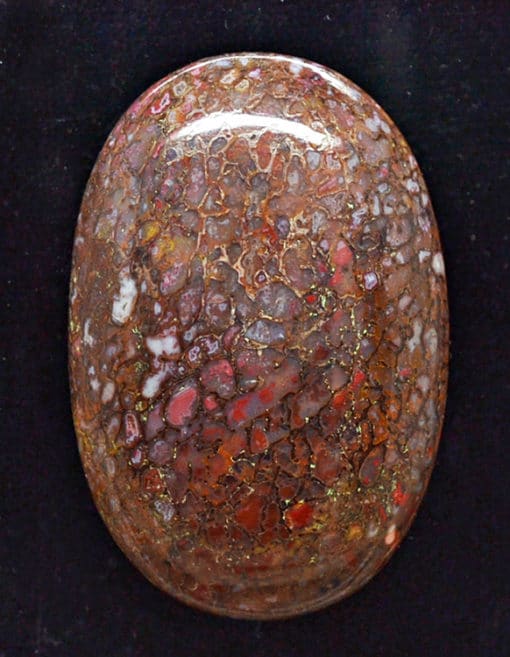 A red and brown stone cabochon on a black background.