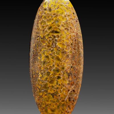 A yellow and brown glass oval on a black background.