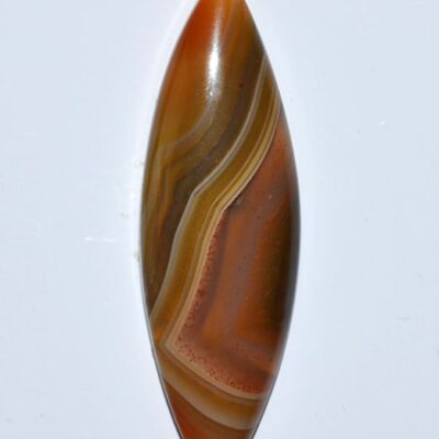 A brown and orange agate pendant on a white surface.