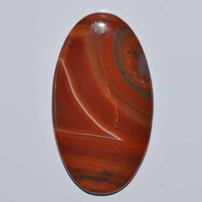 An oval piece of red agate on a white surface.