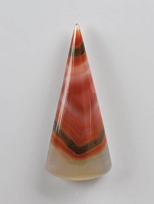 A cone shaped piece of agate on a white surface.