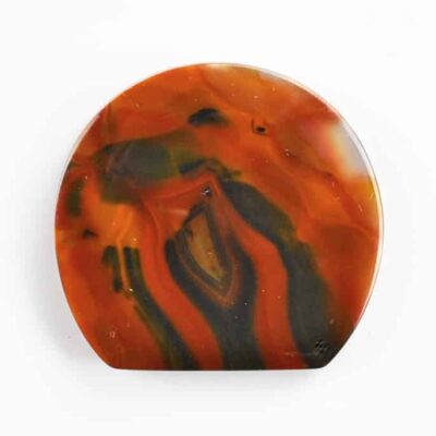 A piece of orange and black agate on a white surface.