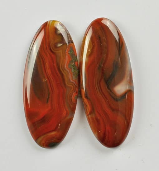A pair of red agate oval cabochons.