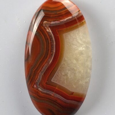An orange and white agate cabochon on a white surface.