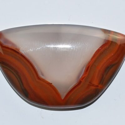 An orange and brown agate pendant on a white surface.