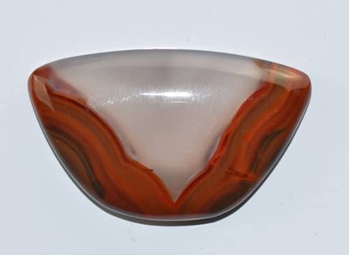 An orange and brown agate pendant on a white surface.