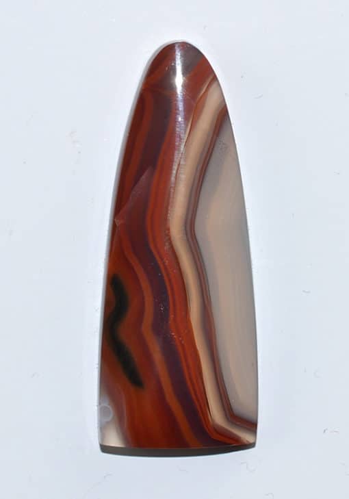 A red and brown agate pendant on a white surface.