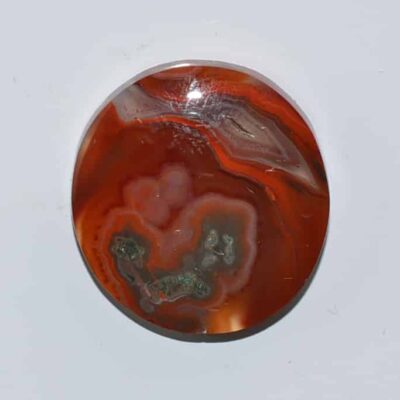 A red agate pendant on a white surface.