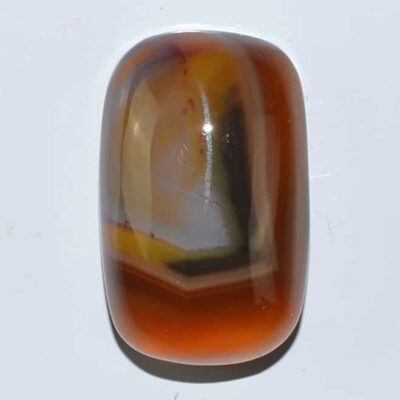 An orange and brown agate cabochon on a white surface.