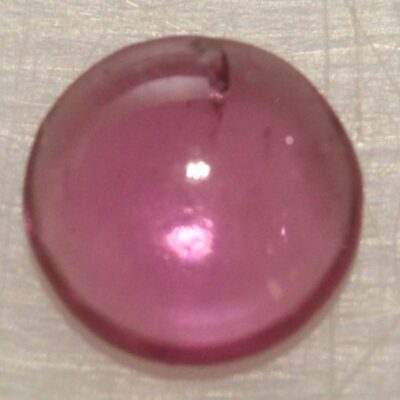 An oval shaped pink stone on a white surface.