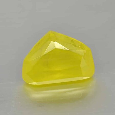 A yellow sapphire on a gray surface.