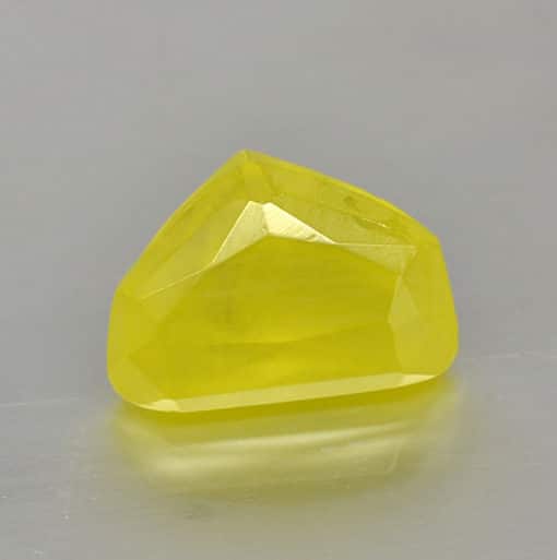 A yellow sapphire on a gray surface.