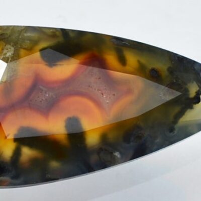 An orange and black agate stone on a white surface.
