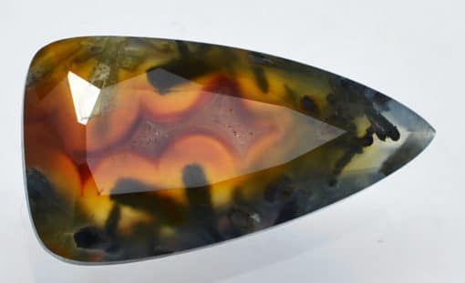 An orange and black agate stone on a white surface.
