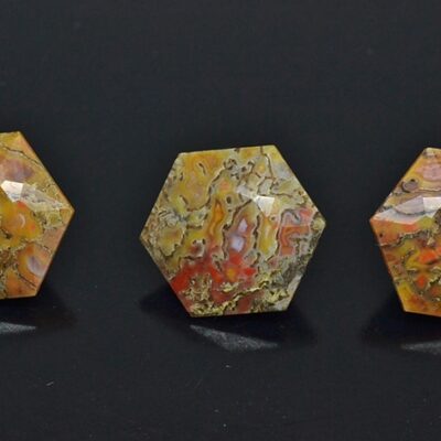 Three pieces of yellow and orange jasper on a black surface.