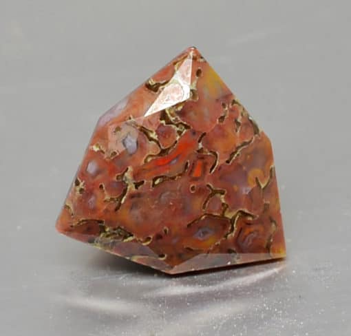 A piece of orange agate on a grey surface.