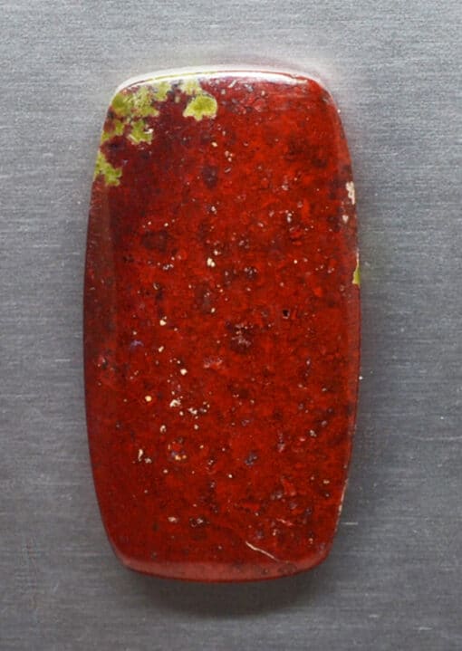 A red stone with green spots on it.