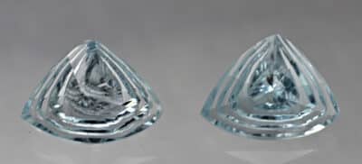 A pair of aquamarine teardrops on a white surface.
